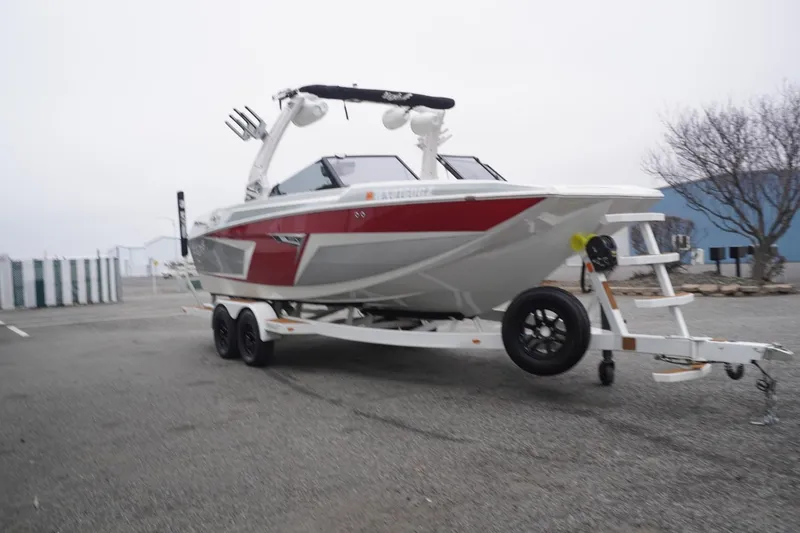 Slide: The Image of 2022 Tigé 22RZX boat on trailer, red and white design, parked outdoors. - 69