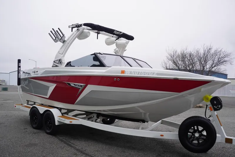 Slide: The Image of 2022 Tigé 22RZX boat on trailer, red and gray design, parked outdoors. - 7