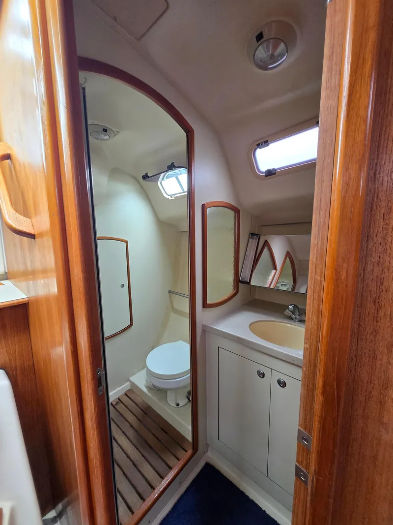 Slide: The Image of 2002 Hunter 356 yacht bathroom with wooden accents, sink, and toilet. - 17