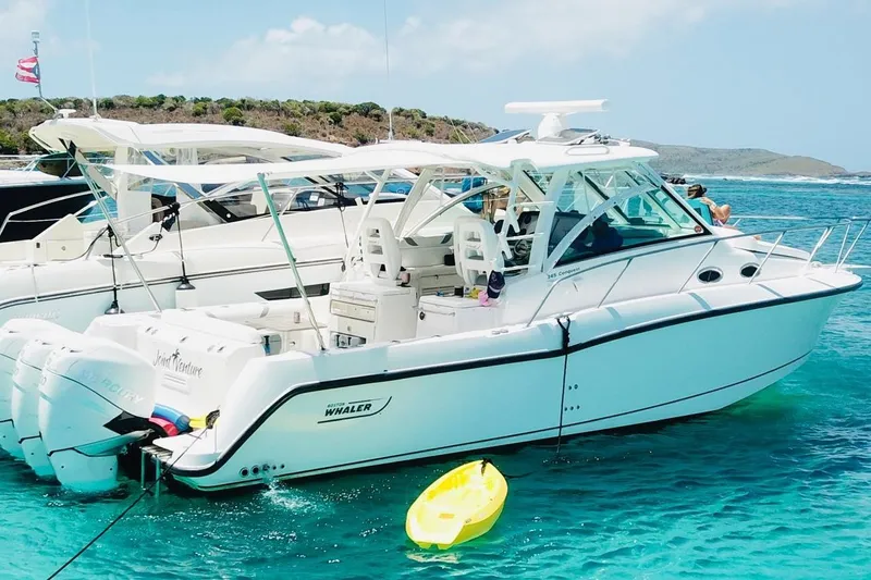 The Image of 2012 Boston Whaler 345 Conquest boat anchored in clear blue water, with a yellow kayak nearby. - 0