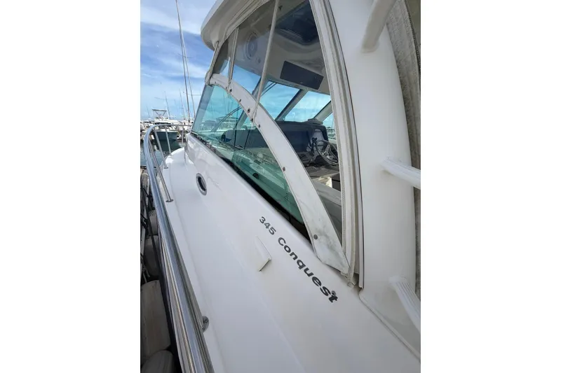 Slide: The Image of 2012 Boston Whaler 345 Conquest boat docked, showcasing sleek design and windows. - 1