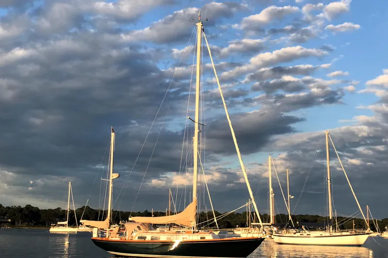 Slide: The Image of Sailboats anchored under a cloudy sky, featuring a 1981 Bristol 40. - 1