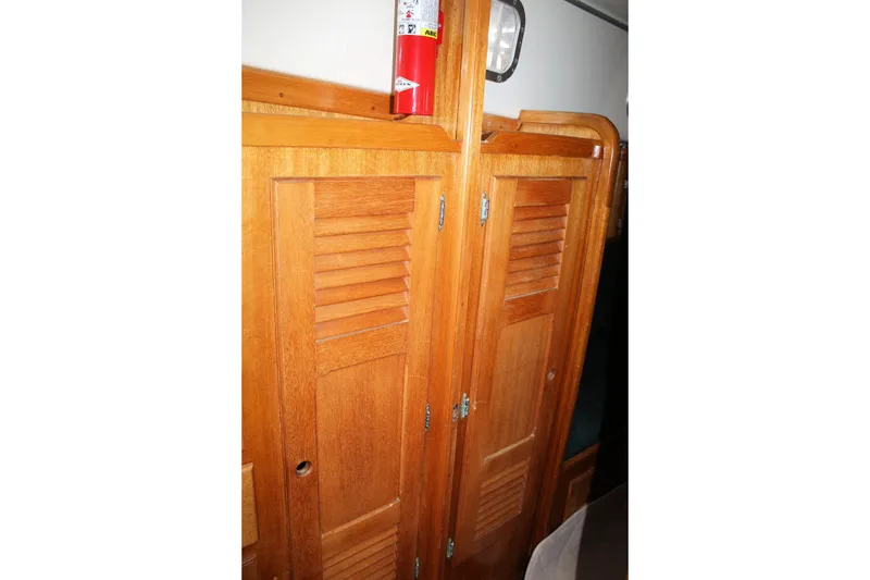 Slide: The Image of Wooden interior of a 1981 Bristol 40 sailboat with louvered doors and a fire extinguisher. - 30