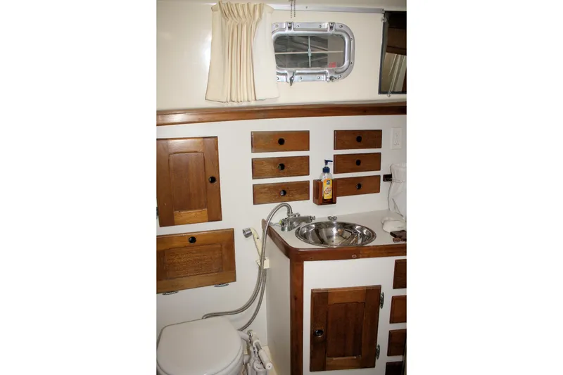 Slide: The Image of 1981 Bristol 40 yacht bathroom with wooden cabinets, stainless steel sink, and porthole window. - 35
