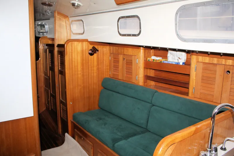 Slide: The Image of Interior of a 1981 Bristol 40 sailboat with wooden cabinetry and green cushioned seating. - 39