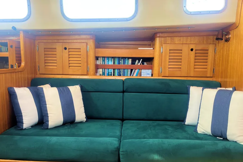 Slide: The Image of 1981 Bristol 40 yacht interior with green sofa, striped pillows, and wooden cabinets. - 8