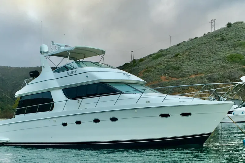 Slide: The Image of 1999 Carver 530 Voyager Pilothouse yacht anchored near a scenic hillside. - 2