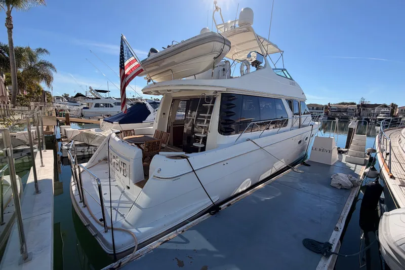 Slide: The Image of 1999 Carver 530 Voyager Pilothouse yacht docked at marina, sunny day, American flag displayed. - 3