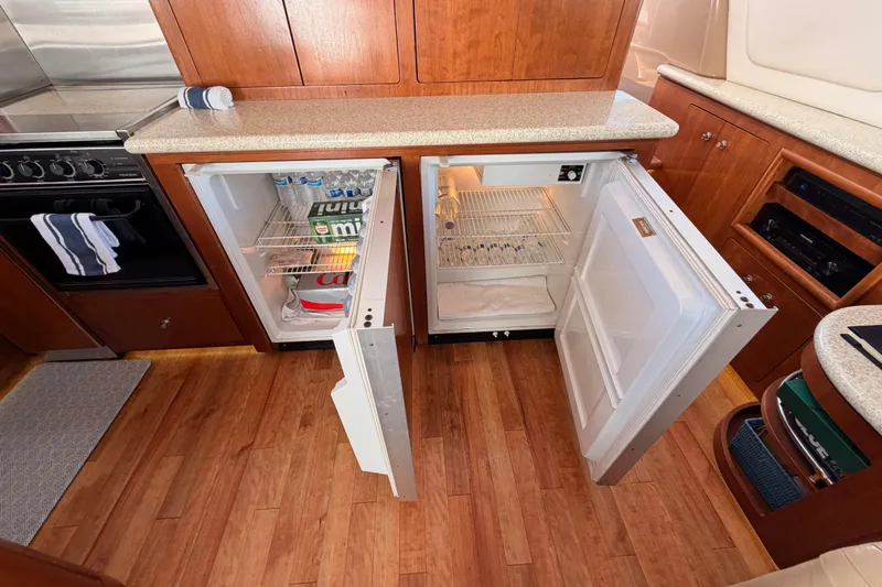 Slide: The Image of 1999 Carver 530 Voyager Pilothouse kitchen with open mini-fridges, wooden flooring, and modern appliances. - 37