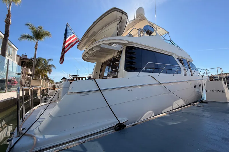 Slide: The Image of 1999 Carver 530 Voyager Pilothouse yacht docked, displaying American flag, palm trees in background. - 7