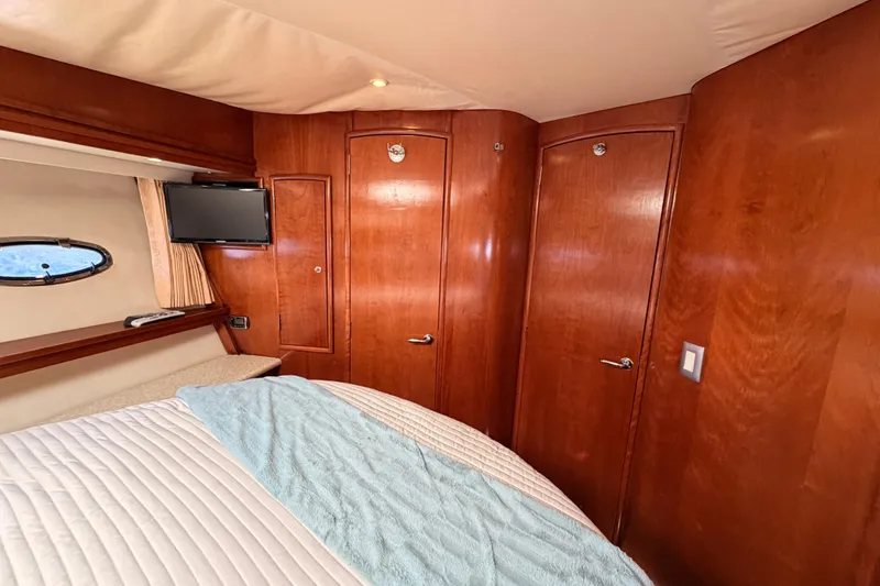 Slide: The Image of Luxurious 1999 Carver 530 Voyager Pilothouse bedroom with wood paneling and porthole window. - 83