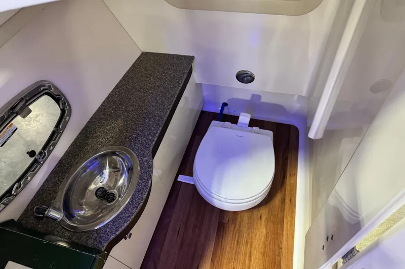 Slide: The Image of 2019 Chaparral 317 SSX boat bathroom with sink, toilet, and wood flooring. - 13