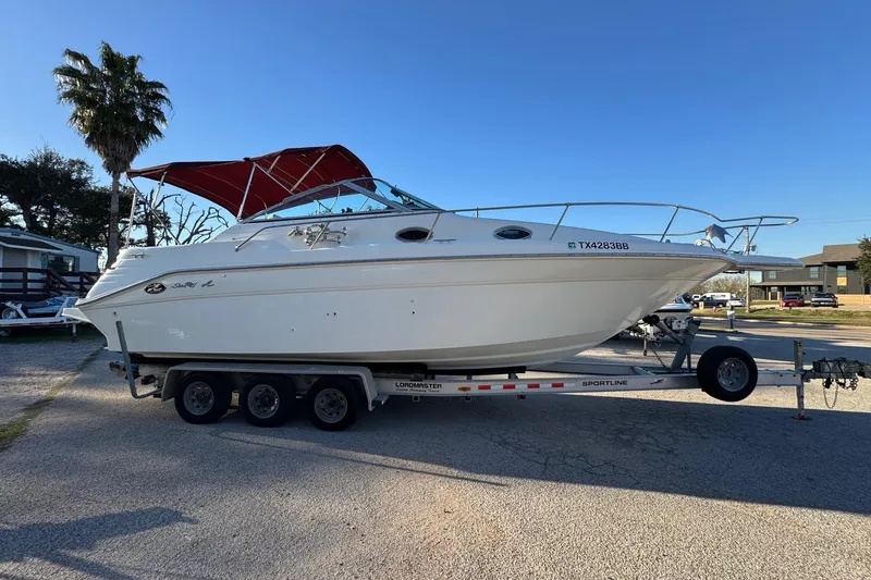 Slide: The Image of 1994 Sea Ray 270 Sundancer boat on trailer with red canopy, parked outdoors. - 2