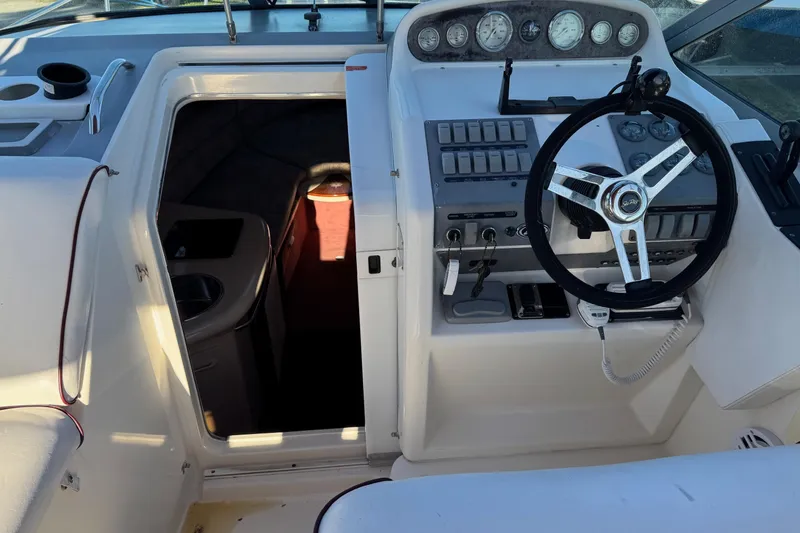 Slide: The Image of 1994 Sea Ray 270 Sundancer cockpit with steering wheel and cabin entrance. - 29