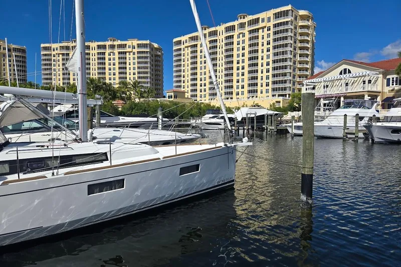 Slide: The Image of 2023 Beneteau Oceanis 38.1 yacht docked in marina with tall buildings in background. - 13