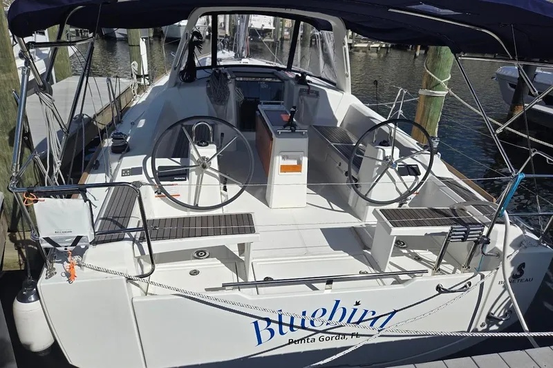 Slide: The Image of 2023 Beneteau Oceanis 38.1 sailboat docked, featuring dual steering wheels and spacious cockpit. - 2