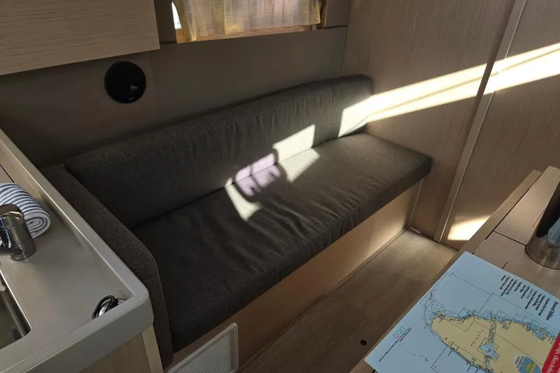 Slide: The Image of 2023 Beneteau Oceanis 38.1 interior with sofa, map, and sunlight. - 38
