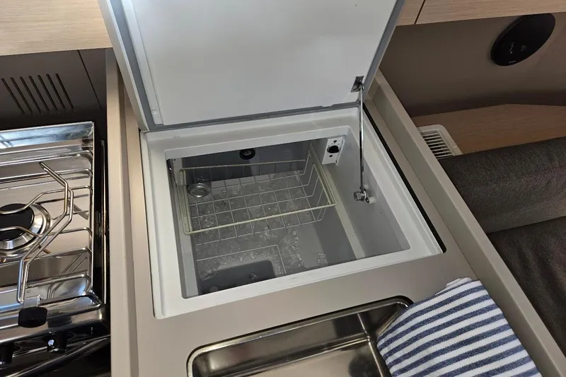 Slide: The Image of Beneteau Oceanis 38.1 yacht kitchen with open fridge, stove, and striped towel, 2023 model. - 47