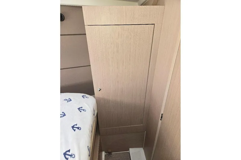 Slide: The Image of Interior cabin of 2023 Beneteau Oceanis 38.1 yacht with wooden paneling and anchor-patterned bedding. - 52