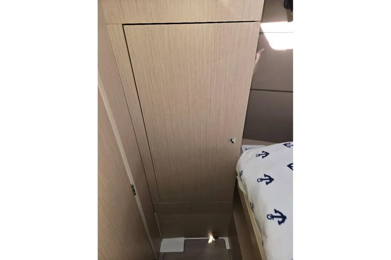Slide: The Image of Interior of 2023 Beneteau Oceanis 38.1 yacht, featuring wooden cabinetry and anchor-patterned bedding. - 54