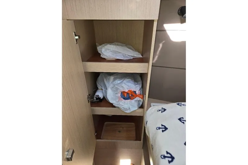 Slide: The Image of Cabinet storage inside 2023 Beneteau Oceanis 38.1 yacht with shelves and nautical-themed bedding. - 55