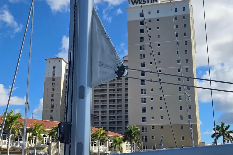 Slide: The Image of 2023 Beneteau Oceanis 38.1 sailboat mast with cityscape and palm trees in background. - 67