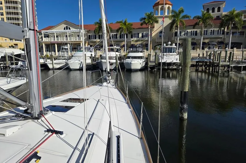 Slide: The Image of 2023 Beneteau Oceanis 38.1 sailboat docked at a marina with palm trees and buildings. - 70