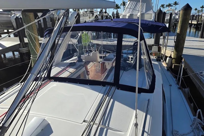 Slide: The Image of 2023 Beneteau Oceanis 38.1 sailboat docked at marina, featuring blue canopy and sleek design. - 78
