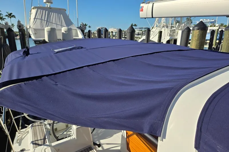 Slide: The Image of 2023 Beneteau Oceanis 38.1 sailboat with blue canvas cover docked at marina. - 79