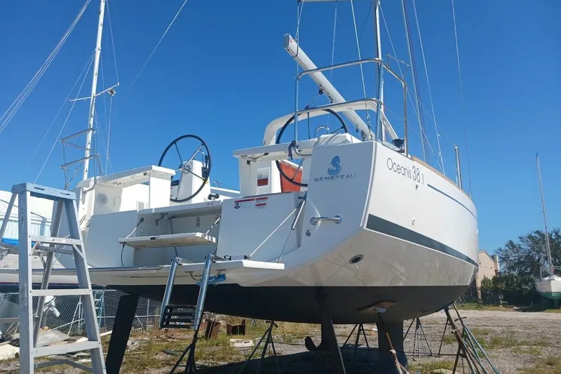 Slide: The Image of 2023 Beneteau Oceanis 38.1 sailboat on land, rear view with clear blue sky. - 92