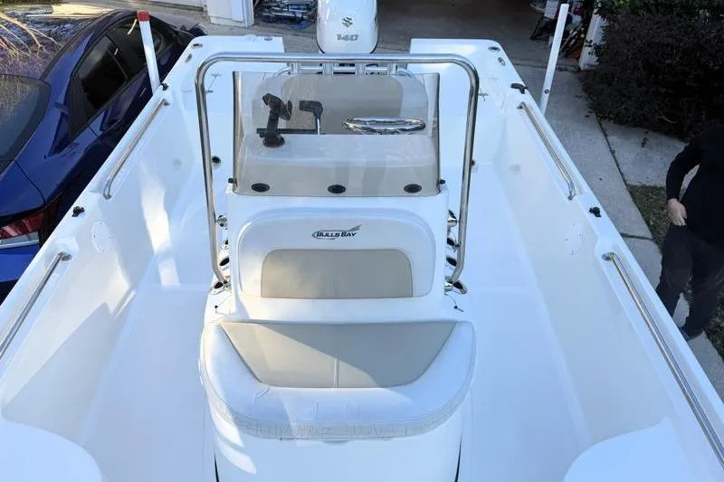 Slide: The Image of 2019 Bulls Bay 2000 boat interior with seating and console, parked beside a blue car. - 19