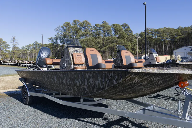 Slide: The Image of 2026 Avid 20 Rogue CC boat with camouflage design on a trailer, parked outdoors. - 2