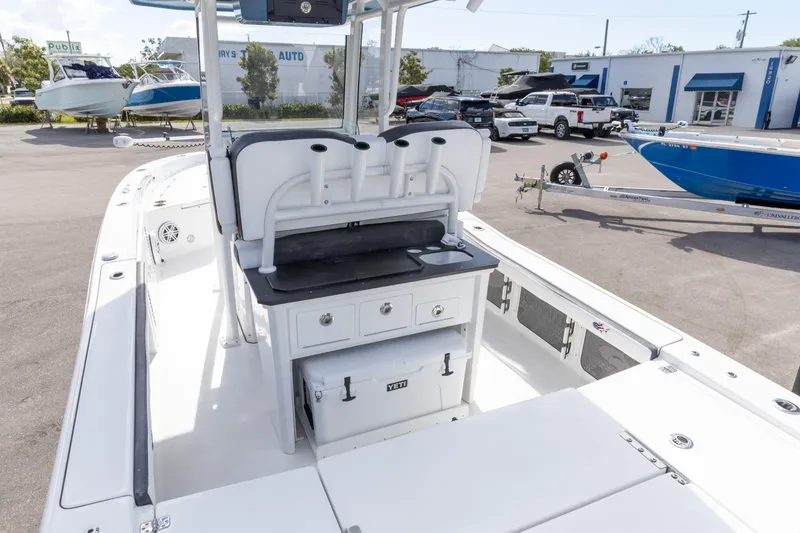 Slide: The Image of 2024 Crevalle 26 HCO boat interior with seating and storage, parked in a dealership lot. - 14