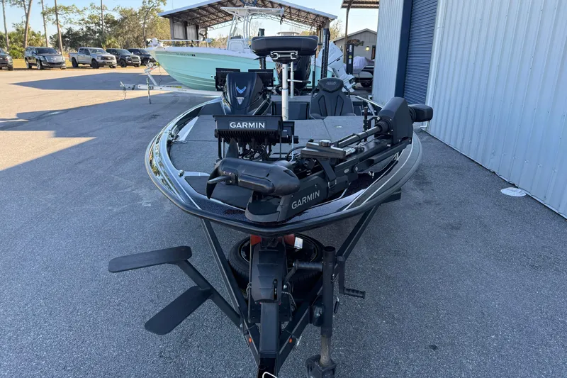 Slide: The Image of 2023 Skeeter FXR20 Select boat with Garmin equipment, parked outdoors near a metal building. - 9