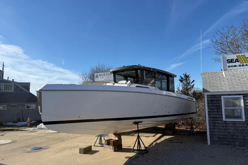 The Image of 2024 Schaefer V33 boat on stands, clear sky, near a building. - 0