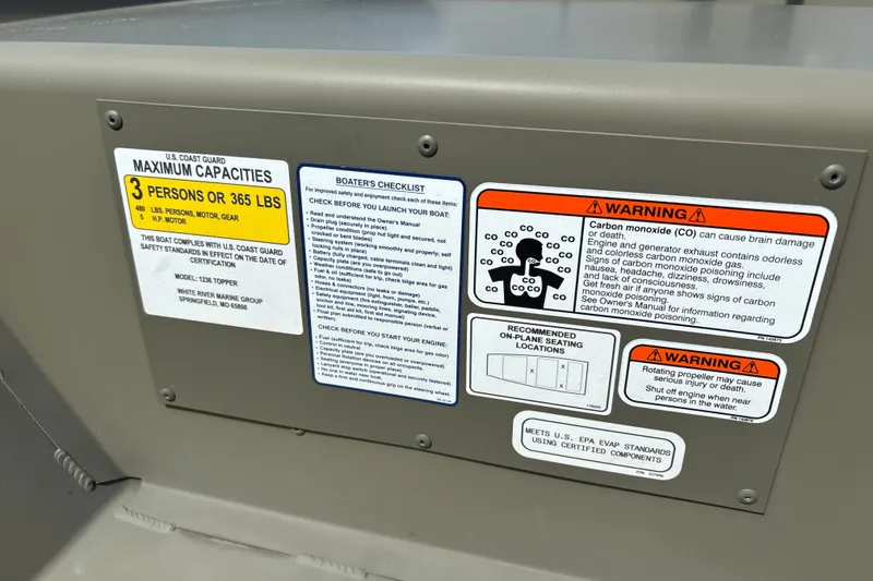Slide: The Image of 2026 Tracker Grizzly 12 Jon boat safety labels and warnings, including capacity and carbon monoxide risks. - 14
