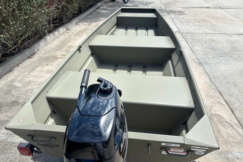 Slide: The Image of 2026 Tracker Grizzly 12 Jon boat with motor, parked on concrete surface. - 13