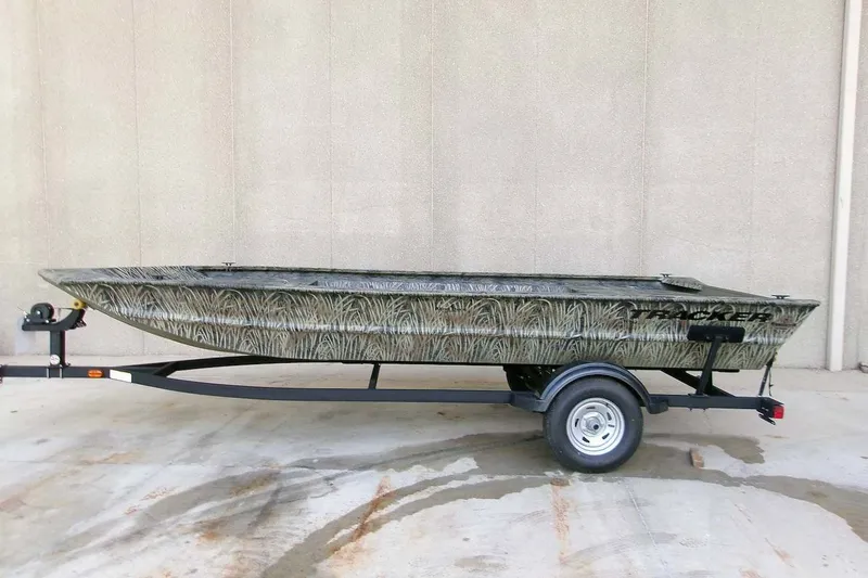 The Image of 2026 Tracker Grizzly 1754 Utility boat on trailer, camo design, parked outdoors. - 0