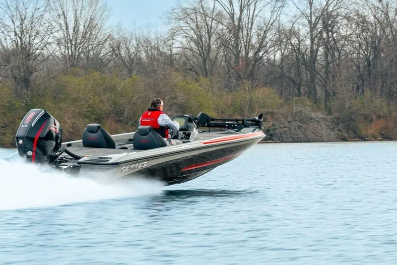 The Image of 2027 Caymas 201 Pro boat speeding on a lake with trees in the background. - 1