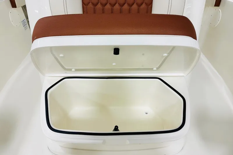Slide: The Image of 2026 Cobia 265 Center Console boat storage compartment with cushioned seat. - 11