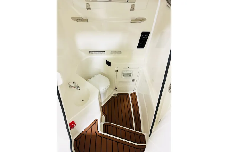 Slide: The Image of 2026 Cobia 265 Center Console boat interior with toilet and wooden flooring. - 12