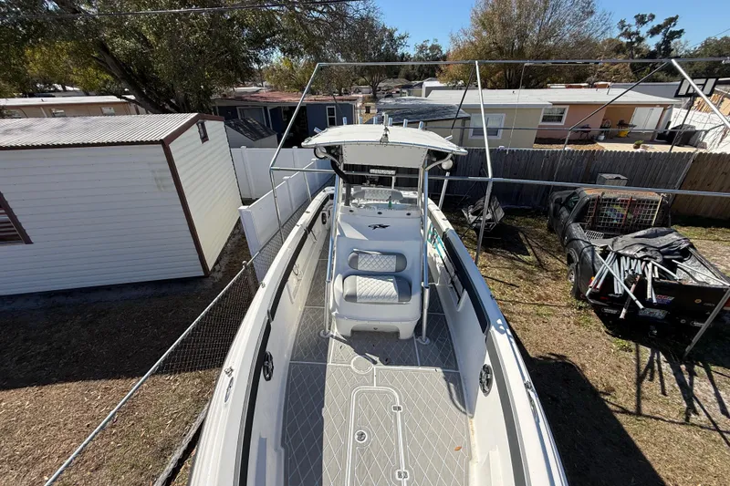 Slide: The Image of 2003 Glasstream 273 SCX boat parked in a residential backyard, surrounded by trees and sheds. - 120