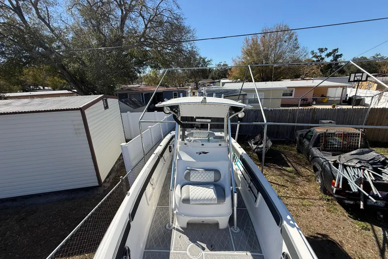 Slide: The Image of 2003 Glasstream 273 SCX boat parked in a residential backyard, surrounded by trees and sheds. - 121