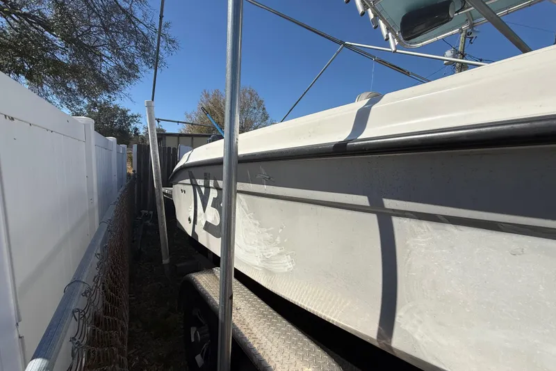 Slide: The Image of 2003 Glasstream 273 SCX boat parked beside a white fence under clear blue sky. - 19