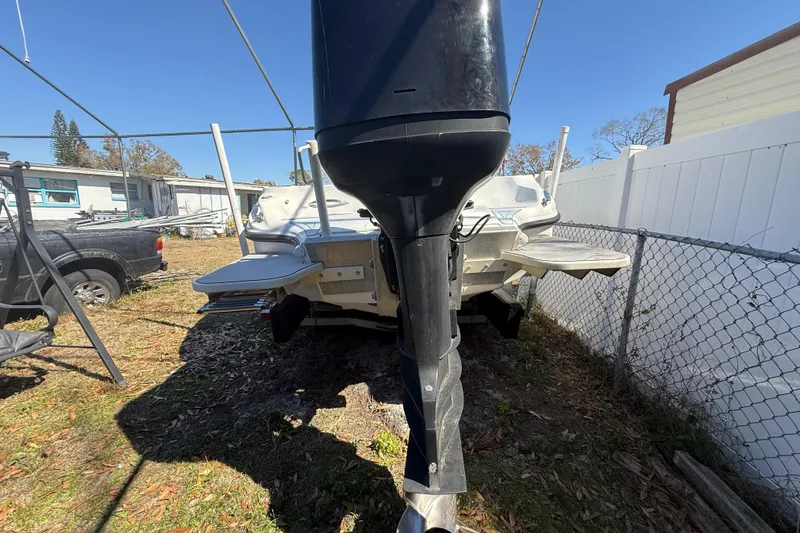 Slide: The Image of 2003 Glasstream 273 SCX boat with outboard motor, parked outdoors near a fence. - 21