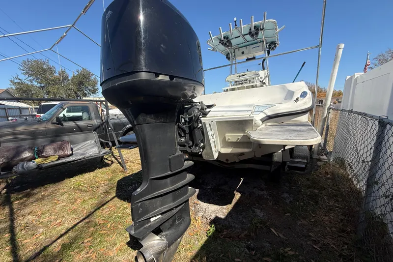 Slide: The Image of 2003 Glasstream 273 SCX boat with outboard motor, parked outdoors on grass. - 24