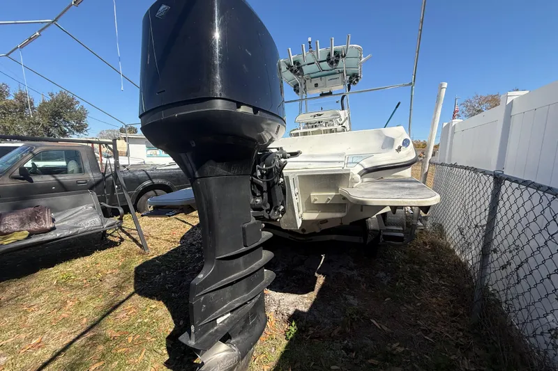 Slide: The Image of 2003 Glasstream 273 SCX boat with outboard motor, parked outdoors near a fence. - 25