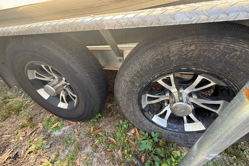 Slide: The Image of Trailer wheels of a 2003 Glasstream 273 SCX boat on grass with metal fender. - 49