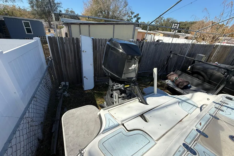 Slide: The Image of 2003 Glasstream 273 SCX boat with outboard motor in a fenced yard. - 50