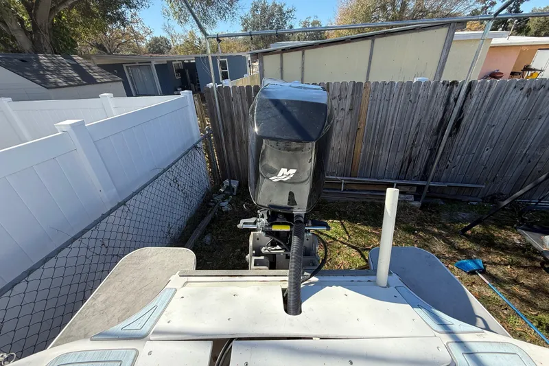 Slide: The Image of 2003 Glasstream 273 SCX boat with outboard motor, parked in a fenced yard. - 54